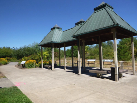 Covered wetland viewing area with benches, garbage cans and informational signage &ndash; next to butterfly garden