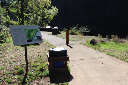 Trailhead to paved trail from parking lot, picnic benches and playground