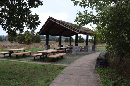 Covered picnic shelter and outdoor picnic tables on hard surface – near parking lot Covered picnic shelter and outdoor picnic tables on hard surface – near parking lot