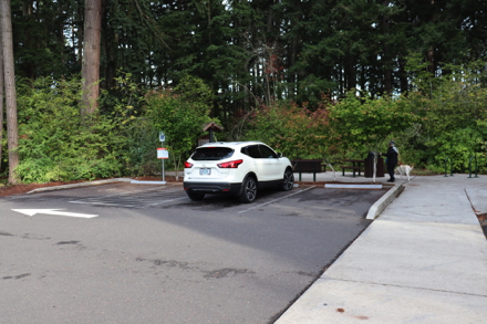 Parking area with trash can, picnic tables, bike rack, kiosk and bench