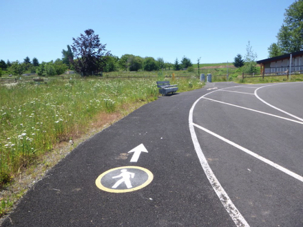 Stenciled graphic of hiker on access trail along entrance road - directs to trails