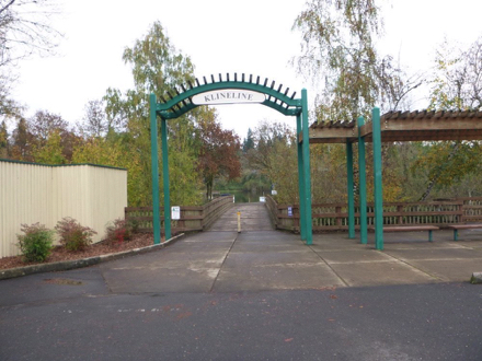 Archway and sign to Klineline Ponds &ndash; hard surface &ndash; benches &ndash; bridge over creek to ponds and amenities