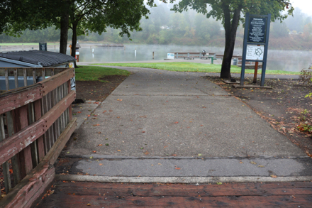 Approaching Pond &ndash; trash can &ndash; rules &ndash; intersecting hard surface pathways &ndash; pier with railing at pond &ndash; benches &ndash; drinking fountain
