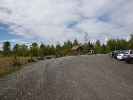 Gravel parking lot with bus and RV parking on the left &ndash; vault toilets and informational kiosk