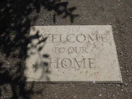 Concrete stepping stone at trail entrance says &lsquo;Welcome to our home&rsquo; &ndash;  may have a lip
