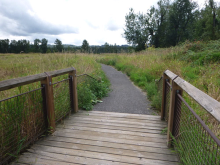 Transition from wooden bridge with railing onto compact gravel trail &ndash; may have a lip &ndash; bridge may be slick when wet