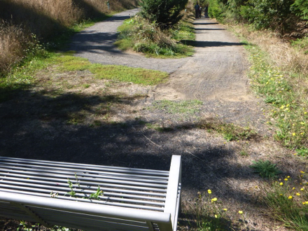 The beginning of the compacted gravel year-round trail has a bench after a short steep grade The beginning of the compacted gravel year-round trail has a bench after a short steep grade