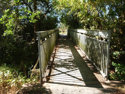 Compacted gravel trail transitions to bridge with railing - there may be a lip at the transition Compacted gravel trail transitions to bridge with railing - there may be a lip at the transition
