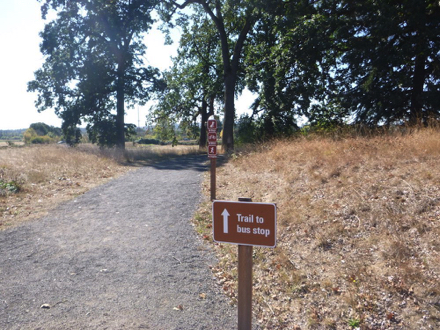 Sign says &ldquo;Trail to bus stop&rdquo; - compacted gravel trail from main parking lot and Wildlife Center